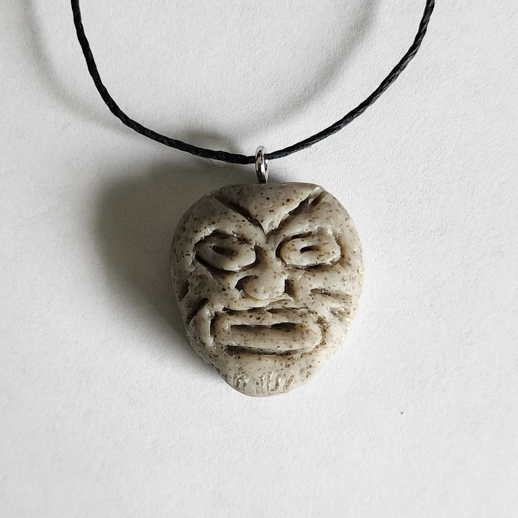 Handmade circular stone-textured ceramic pendant featuring a carved Taíno ancestral face petroglyph on a black cord necklace, inspired by indigenous Puerto Rican rock art.