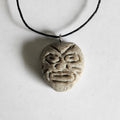 Handmade circular stone-textured ceramic pendant featuring a carved Taíno ancestral face petroglyph on a black cord necklace, inspired by indigenous Puerto Rican rock art.