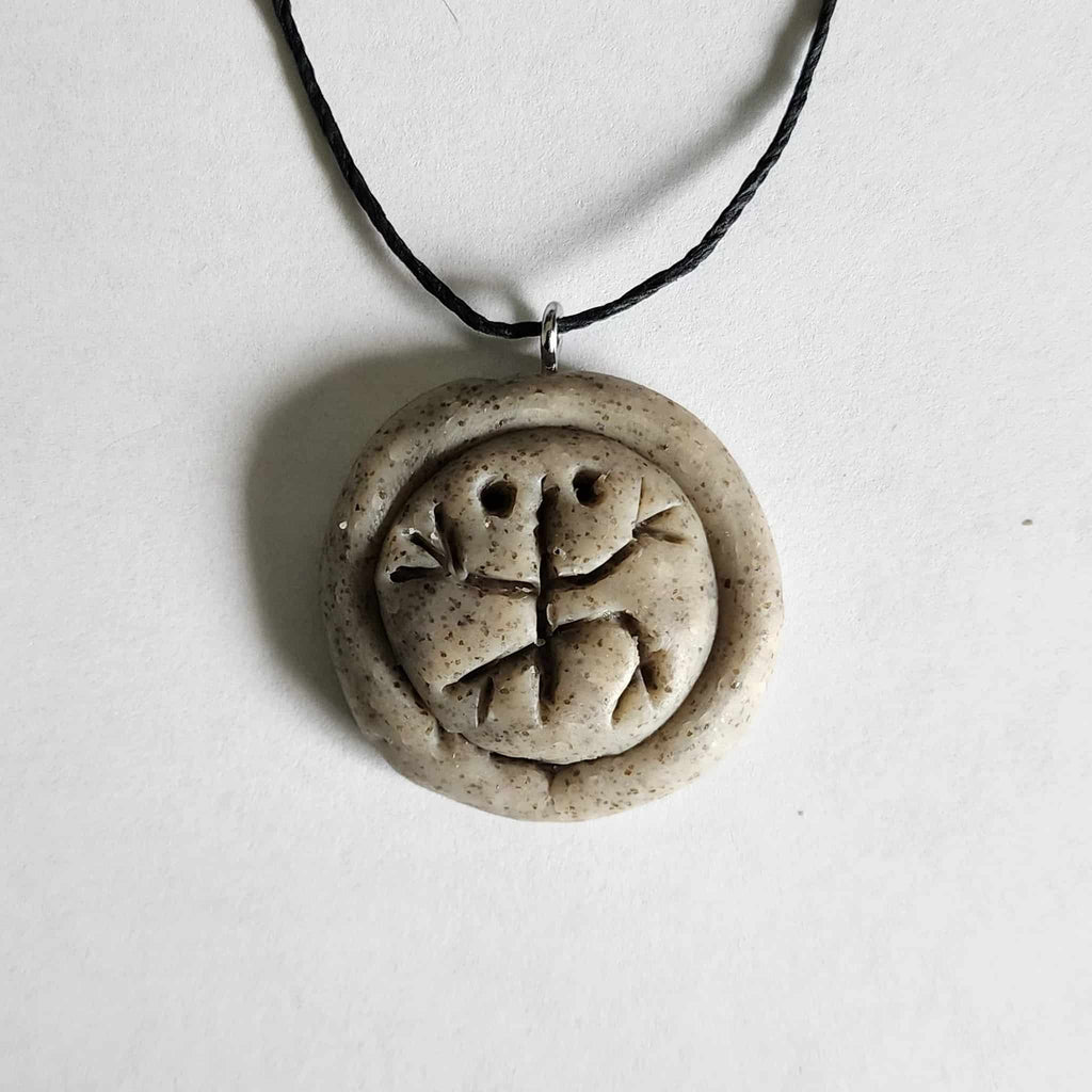 Handmade stone-textured ceramic pendant featuring the traditional Taíno Coquí frog petroglyph on a black cord necklace, inspired by indigenous Puerto Rican art.